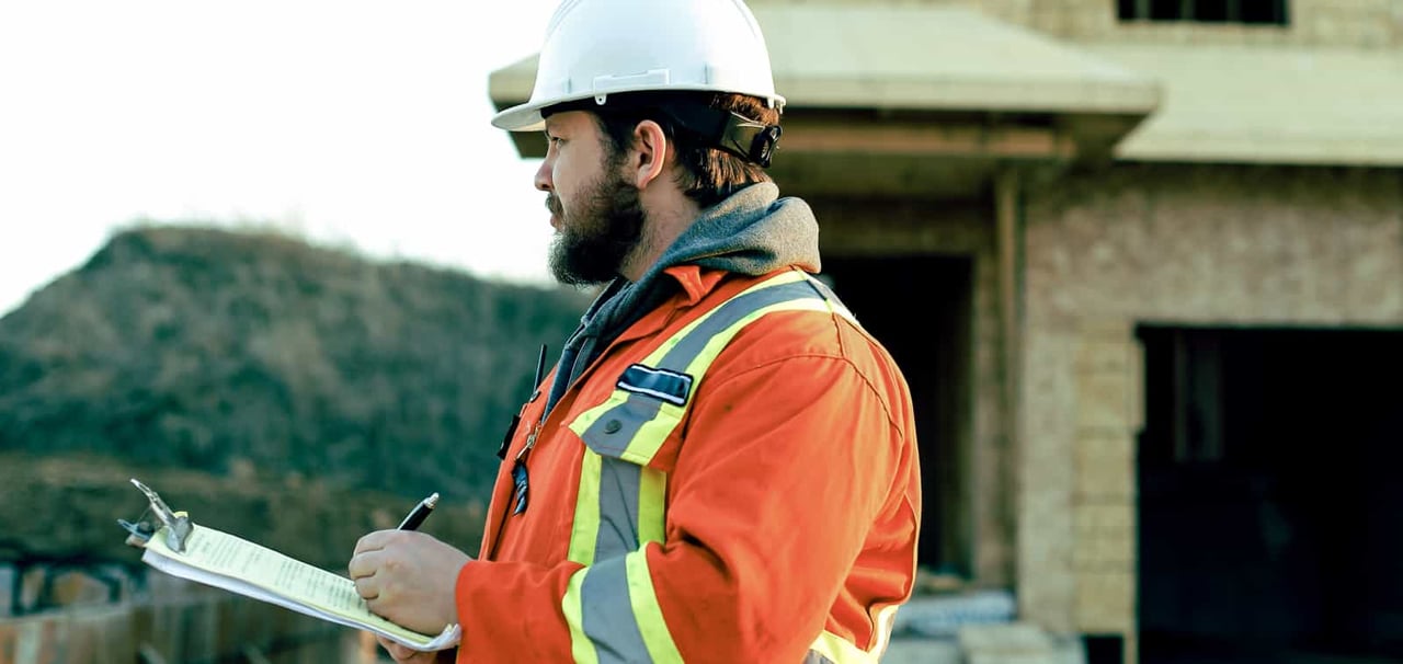 Construction worker running through list on clipboard.