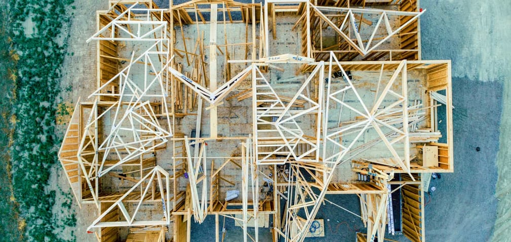 An overhead drone view of a large home with the walls framed but the roof not yet in place.