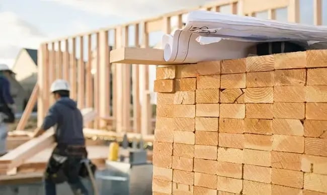 stack of lumber next to a new construction build