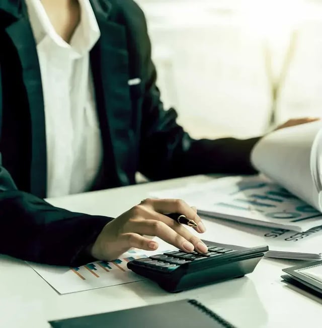 woman using calculator while going over draw administration paperwork