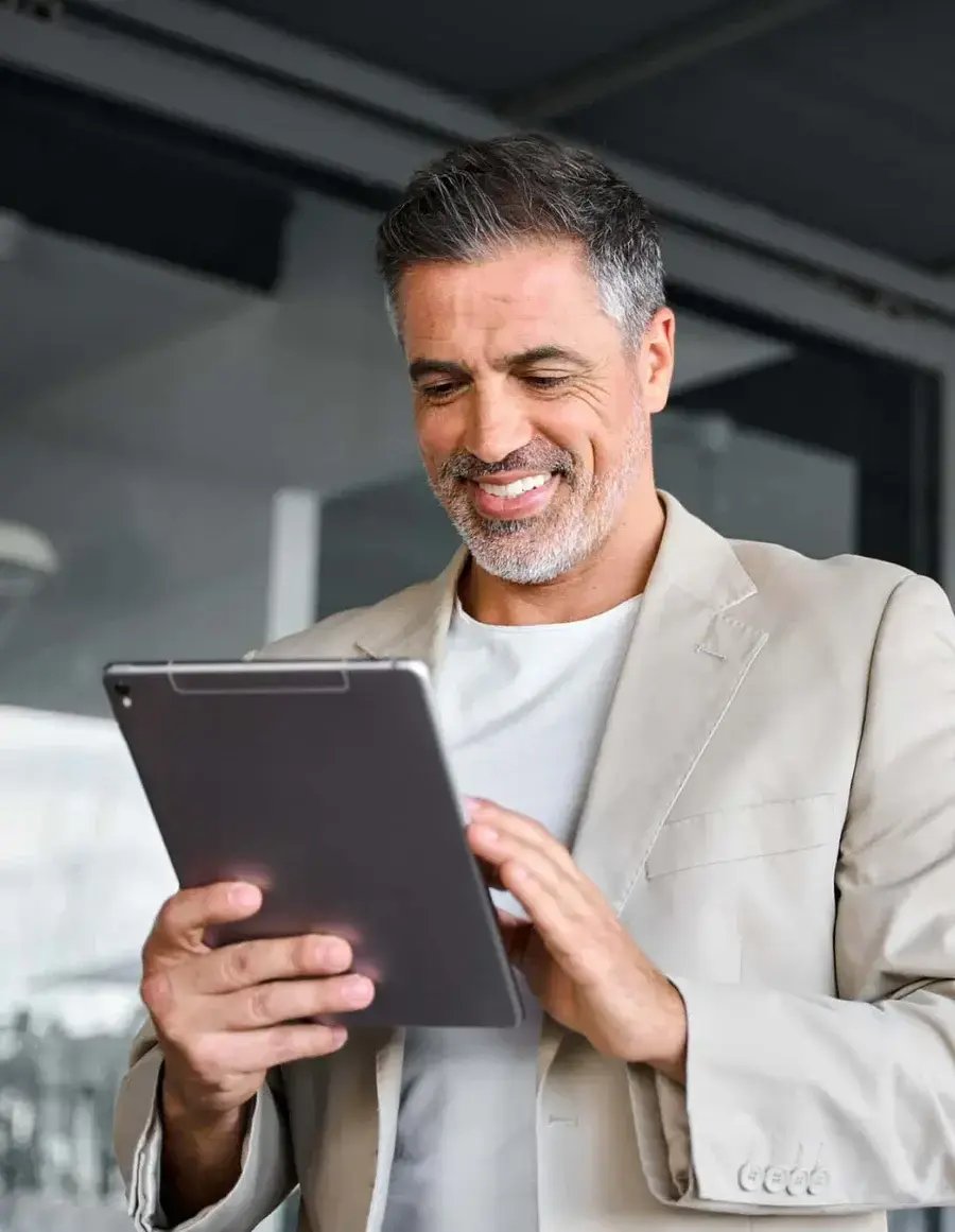 man in blazer smiling while on a tablet