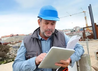 man with hardhat reviewing notes on a tablet