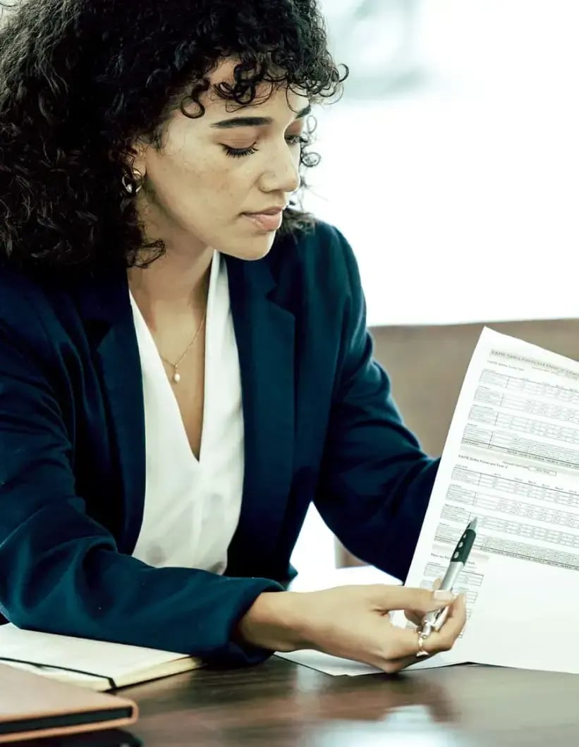 A woman in a blazer reviews paperwork